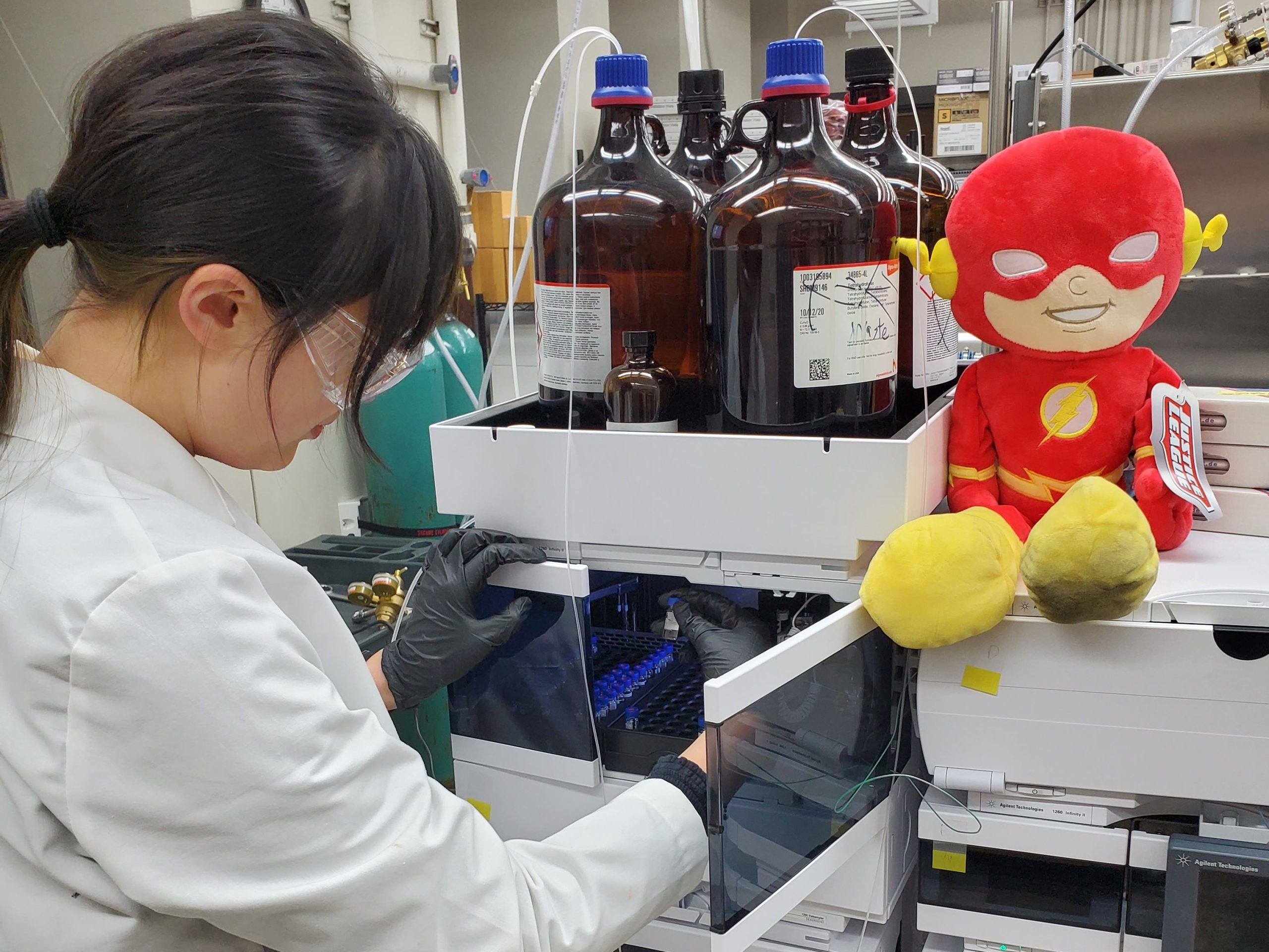 A researcher using and HPLC with a Flash plush sitting on it